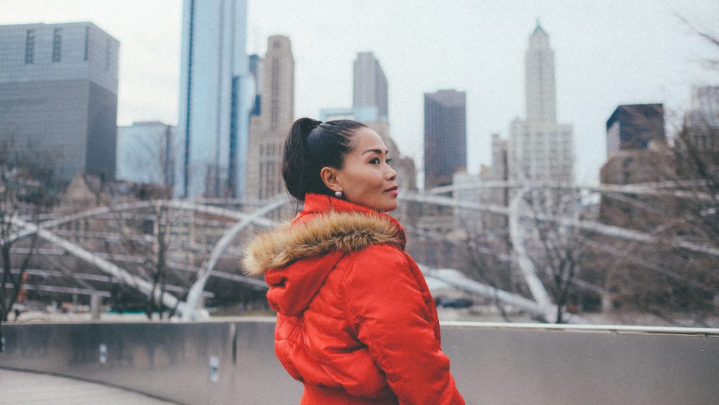 woman wearing winter coat standing outside on bridge