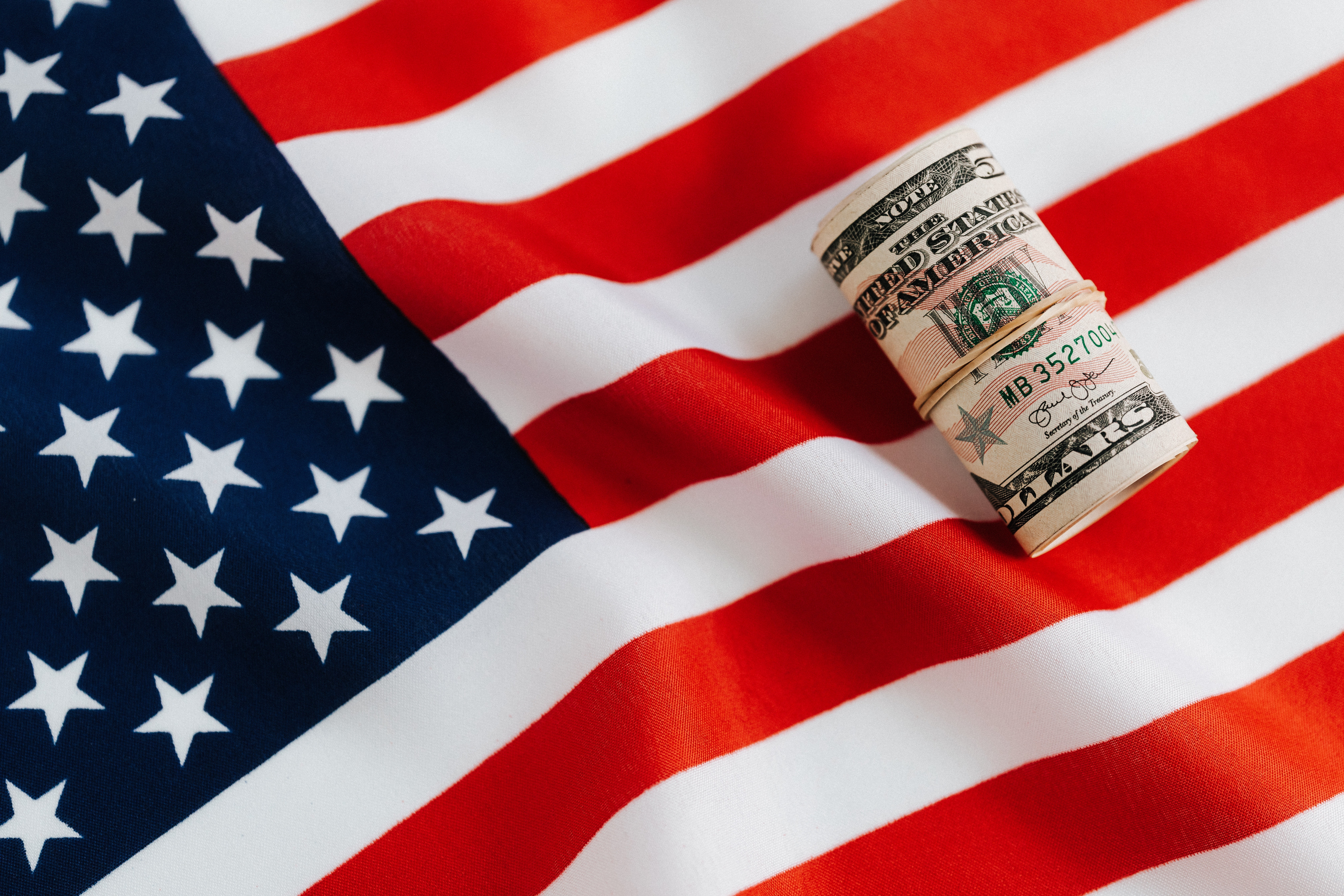 A roll of money places on the American flag.