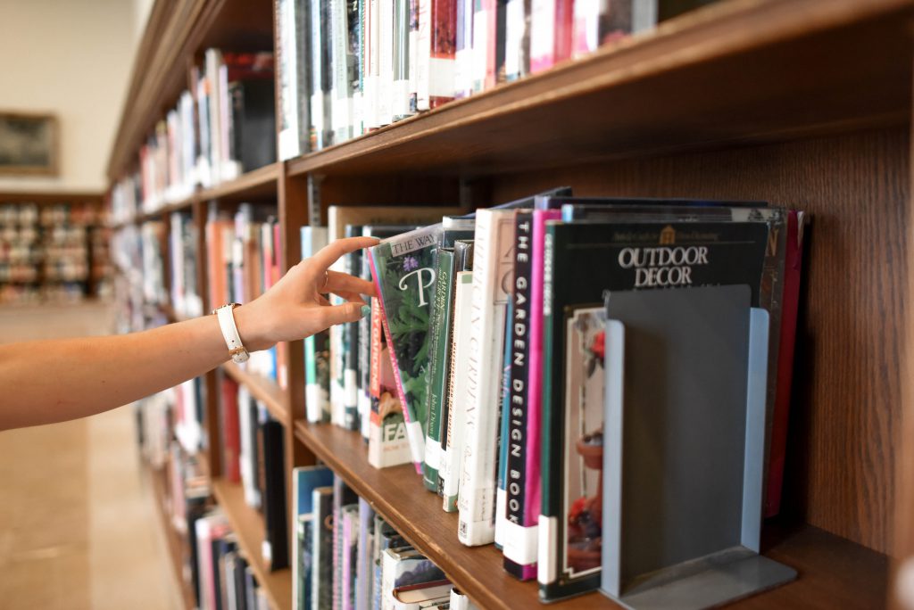 A person looking through a shelf full of books.