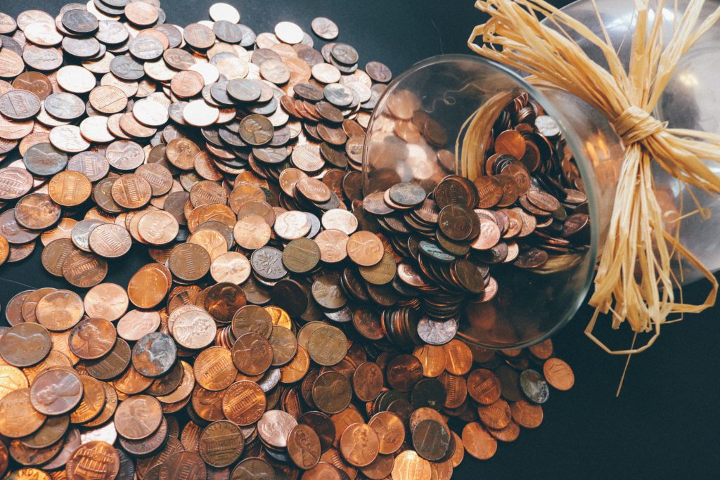 A jar of coins spilled over on a table.