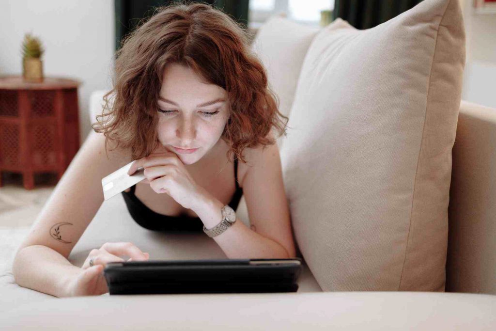 A woman laying on her sofa while shopping online.