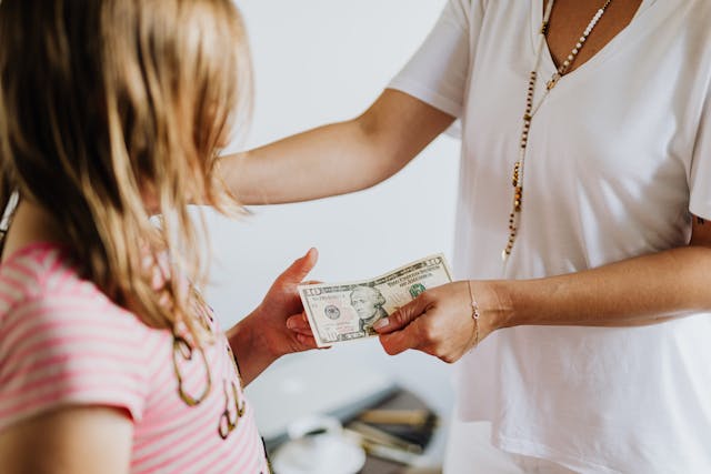 A parent giving their child money.