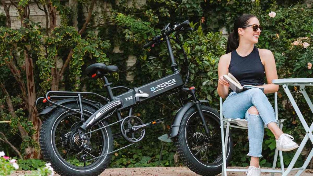 A woman sitting outside next to an electric bike.